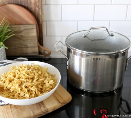 pot of water on a stove next to a bowl of pasta