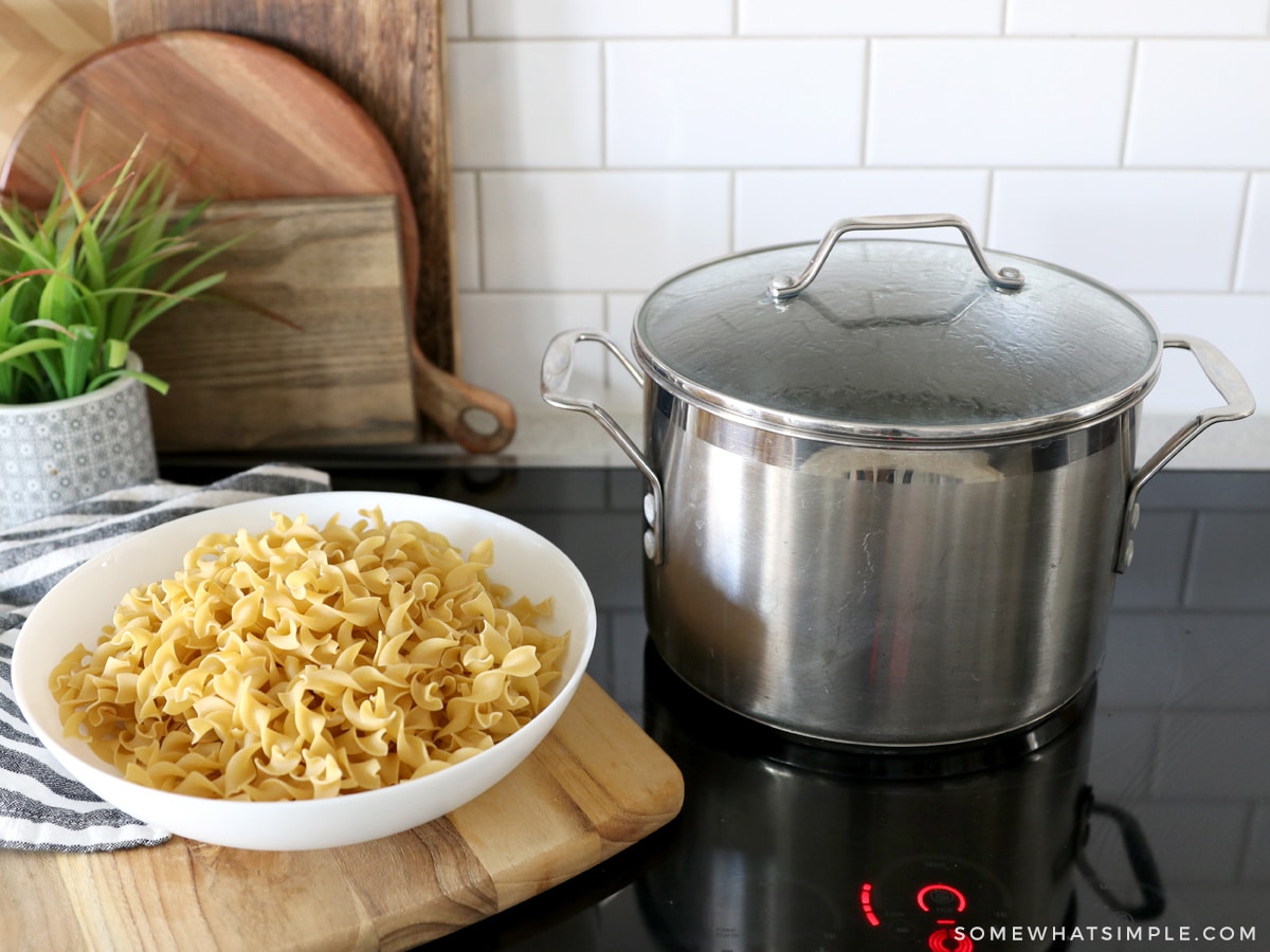 pot of water on a stove next to a bowl of pasta