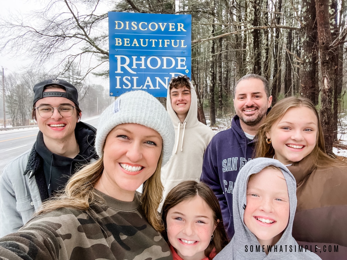 family standing in front of a welcome to rhode island sign