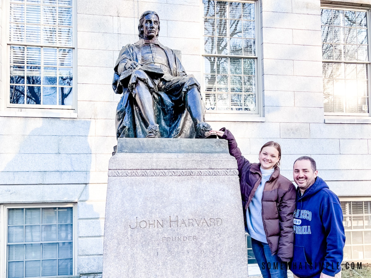 leah and dad standing by the john harvard statue
