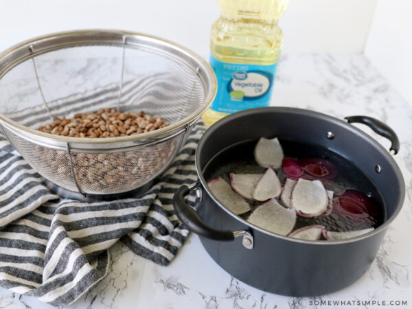 rinsed beans next to a stock pot on water and onions