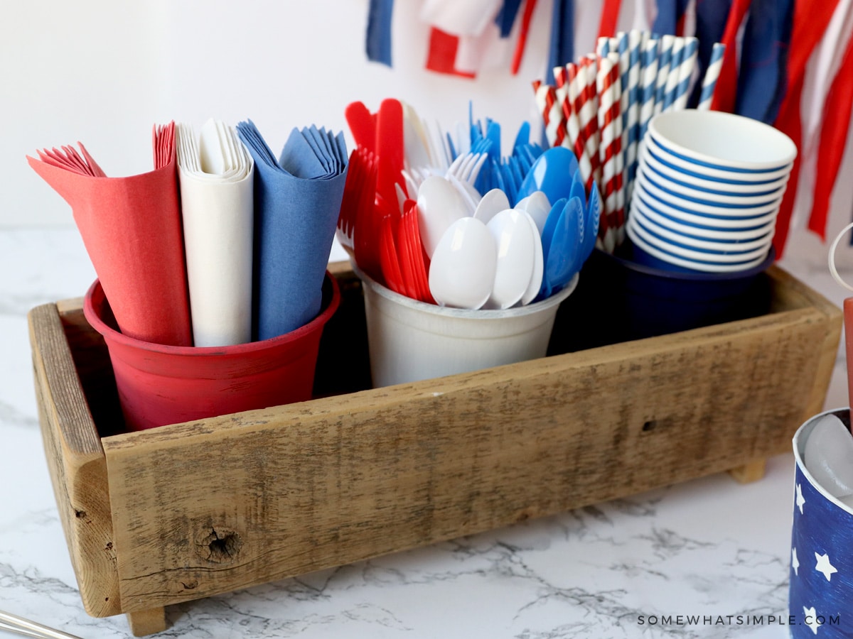 paper goods and cutlery for a bbq in a wood tray