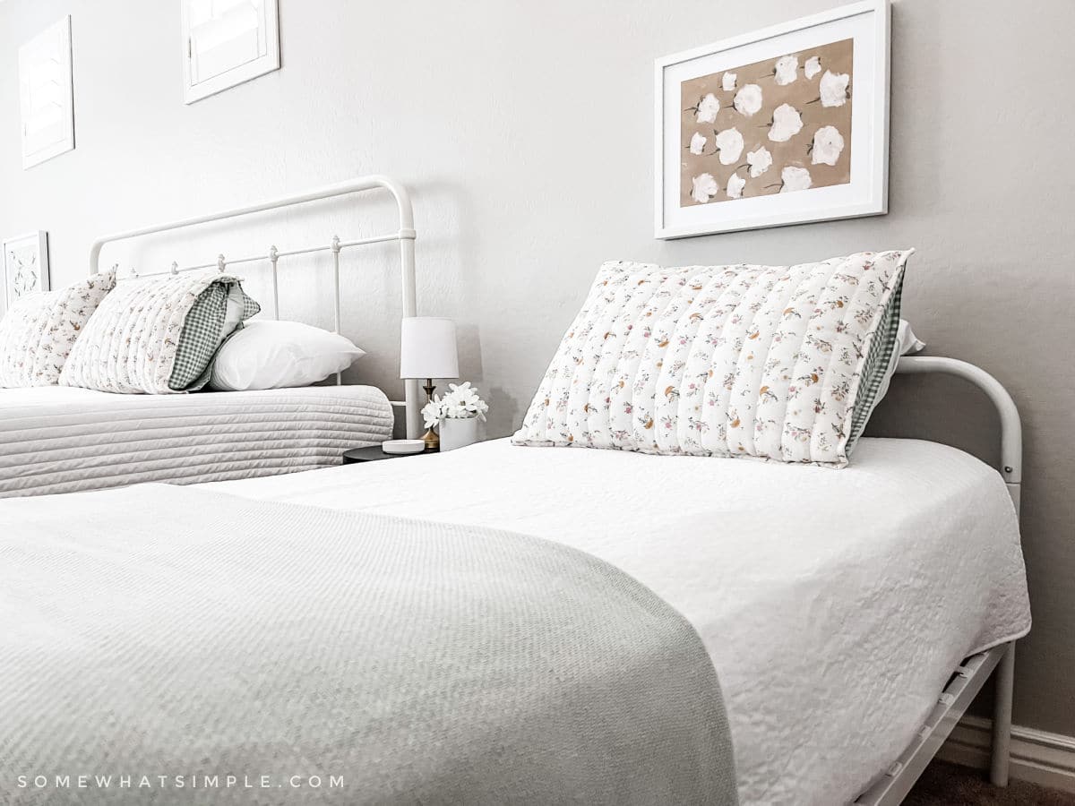 close up of a twin bed with a white quilt and green blanket at the foot
