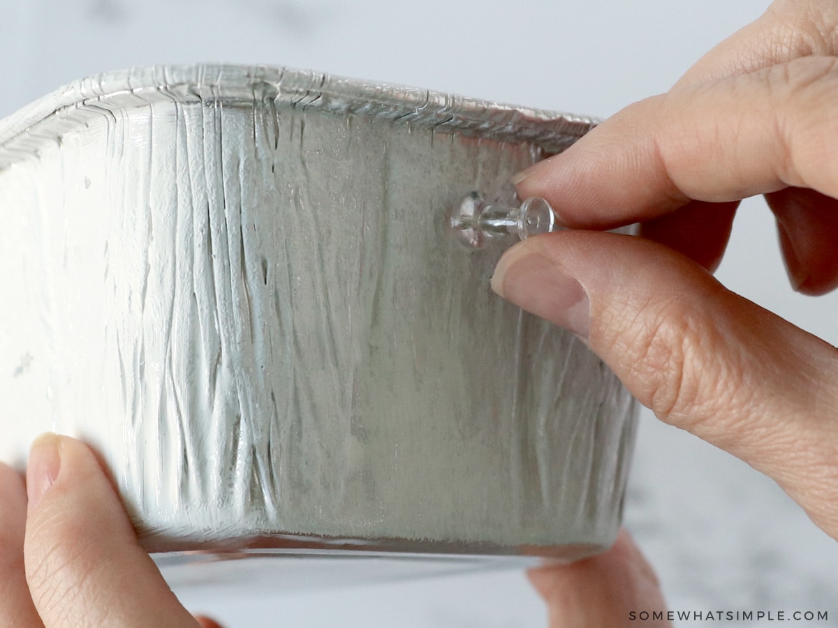 sticking a hole in a bread pan with a thumb tack