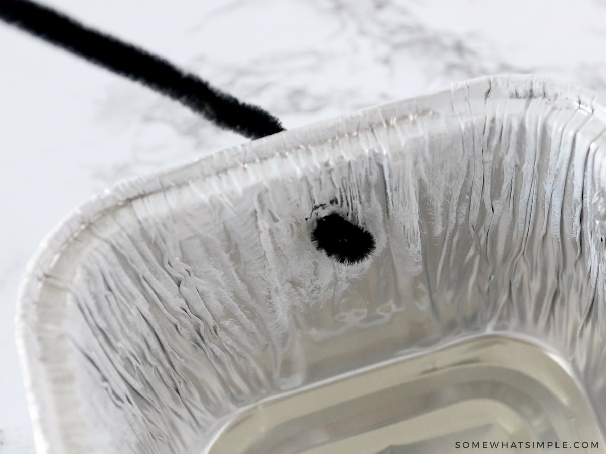 attaching pipe cleaner to a bread pan to make a handle for a bug catcher