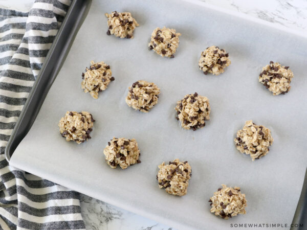 adding spoonfuls of cookie dough to a baking sheet