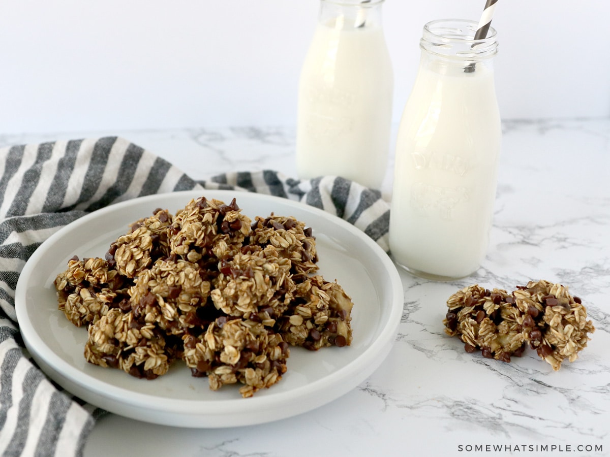 healthy banana oatmeal cookies on a white plate next to two glases of milk