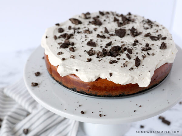 decorating cheesecake with whipped cream and crushed oreos