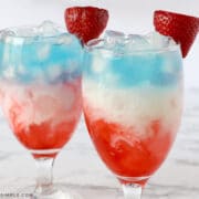 layred glasses with red, white, and blue, liquid and a strawberry on top
