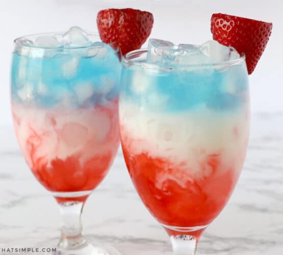 layred glasses with red, white, and blue, liquid and a strawberry on top