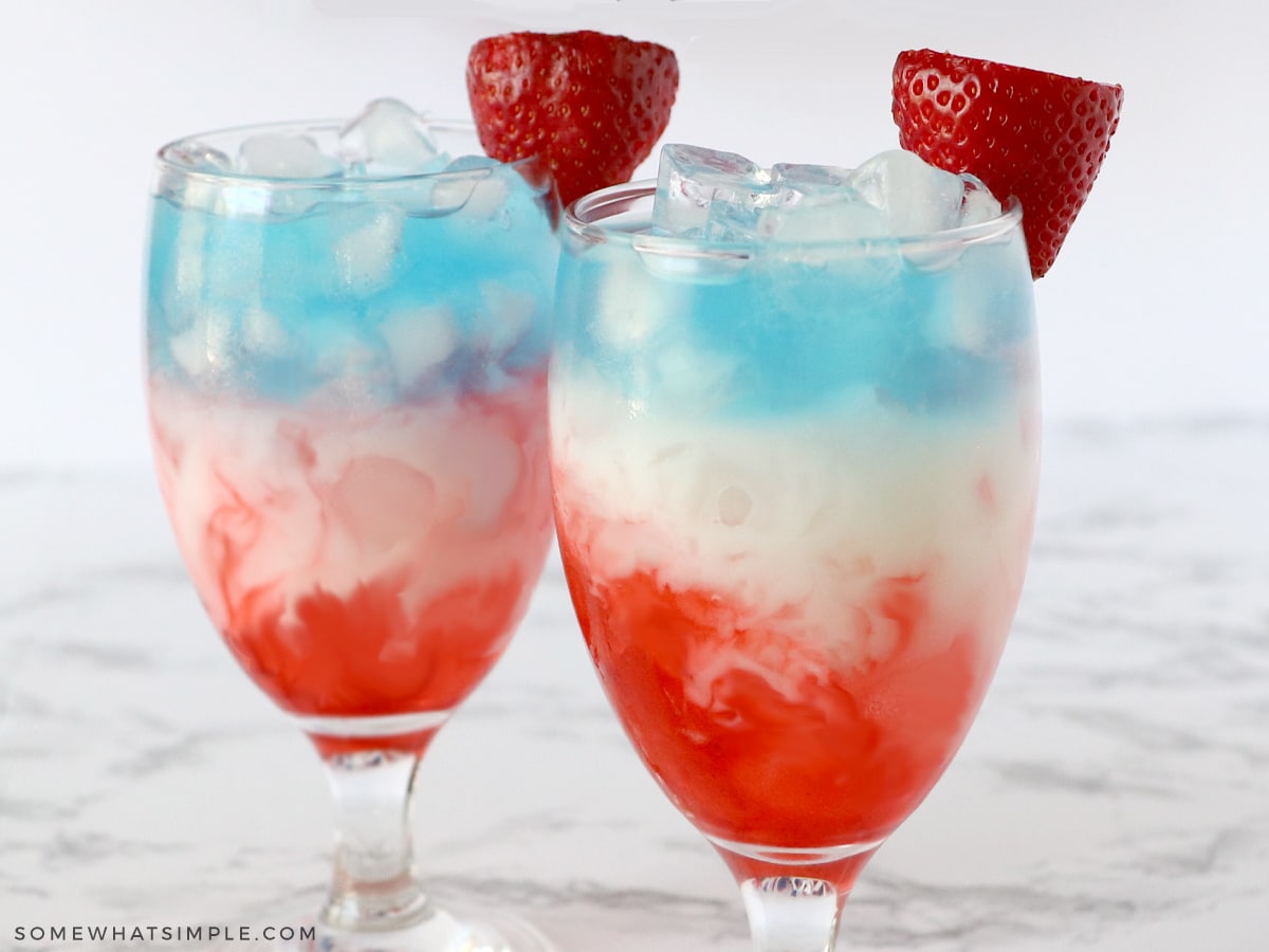 layred glasses with red, white, and blue, liquid and a strawberry on top