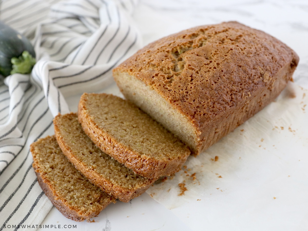 sliced zucchini bread on the counter next to fresh zucchini