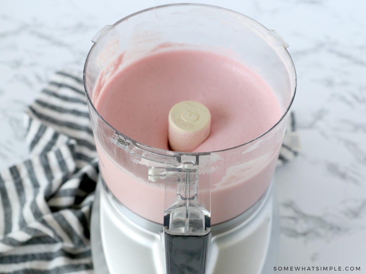 blending strawberry cheesecake frozen yogurt in a food processor