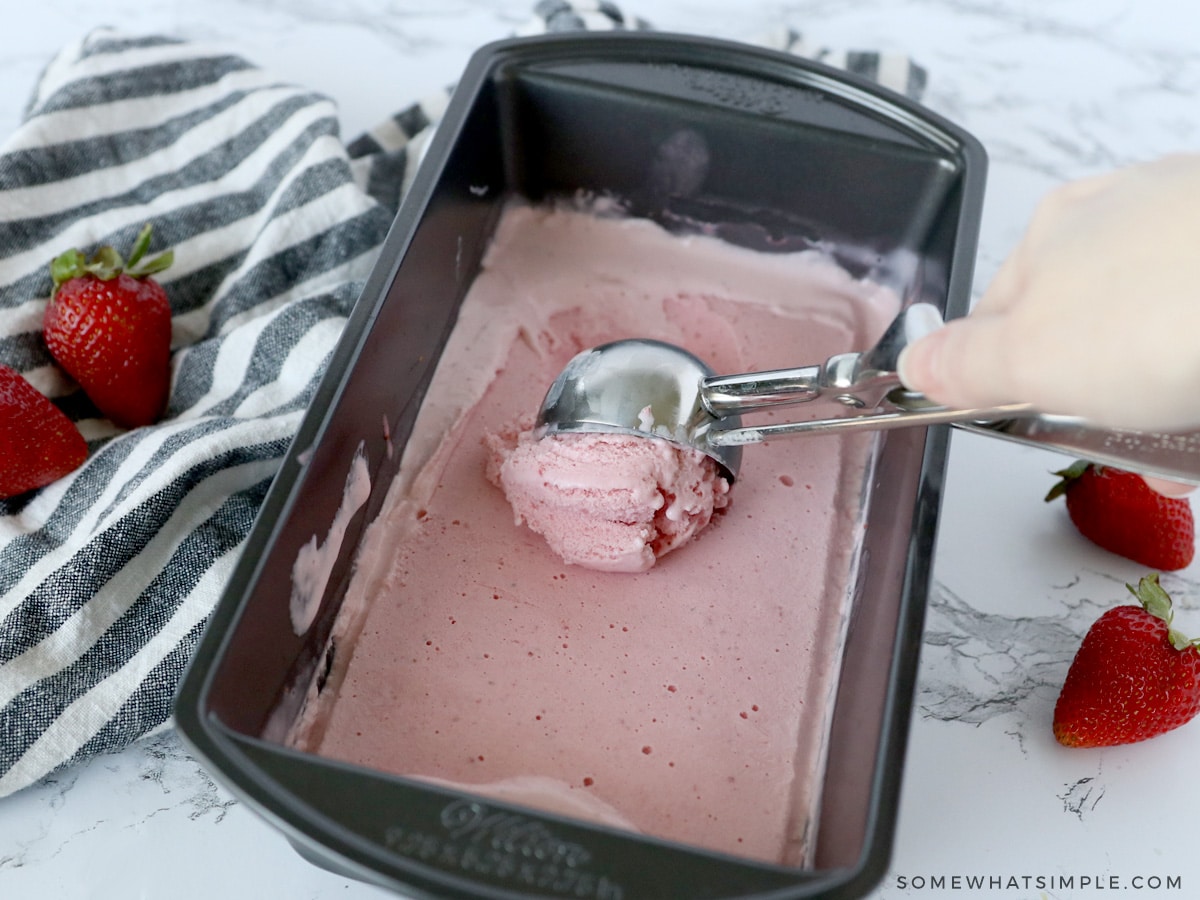 scooping strawberry frozen yogurt out of a bread pan