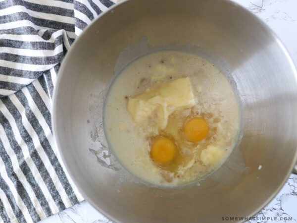 adding eggs to the yeast in a mixing bowl