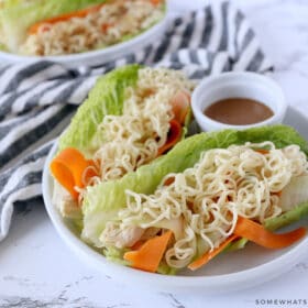 thai chicken lettuce wraps plated next to a striped towel