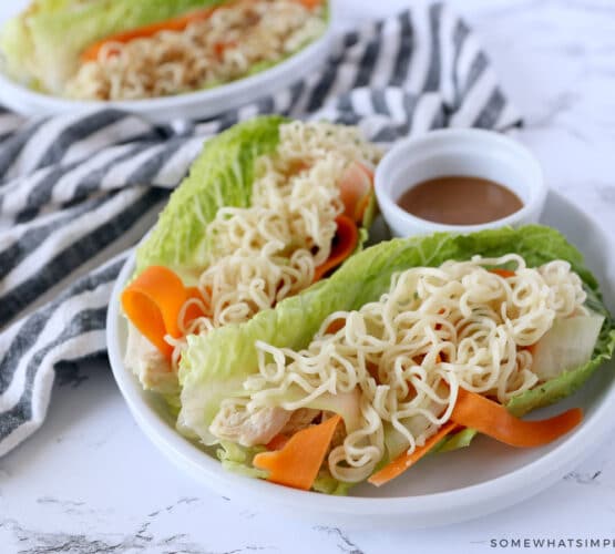 thai chicken lettuce wraps plated next to a striped towel