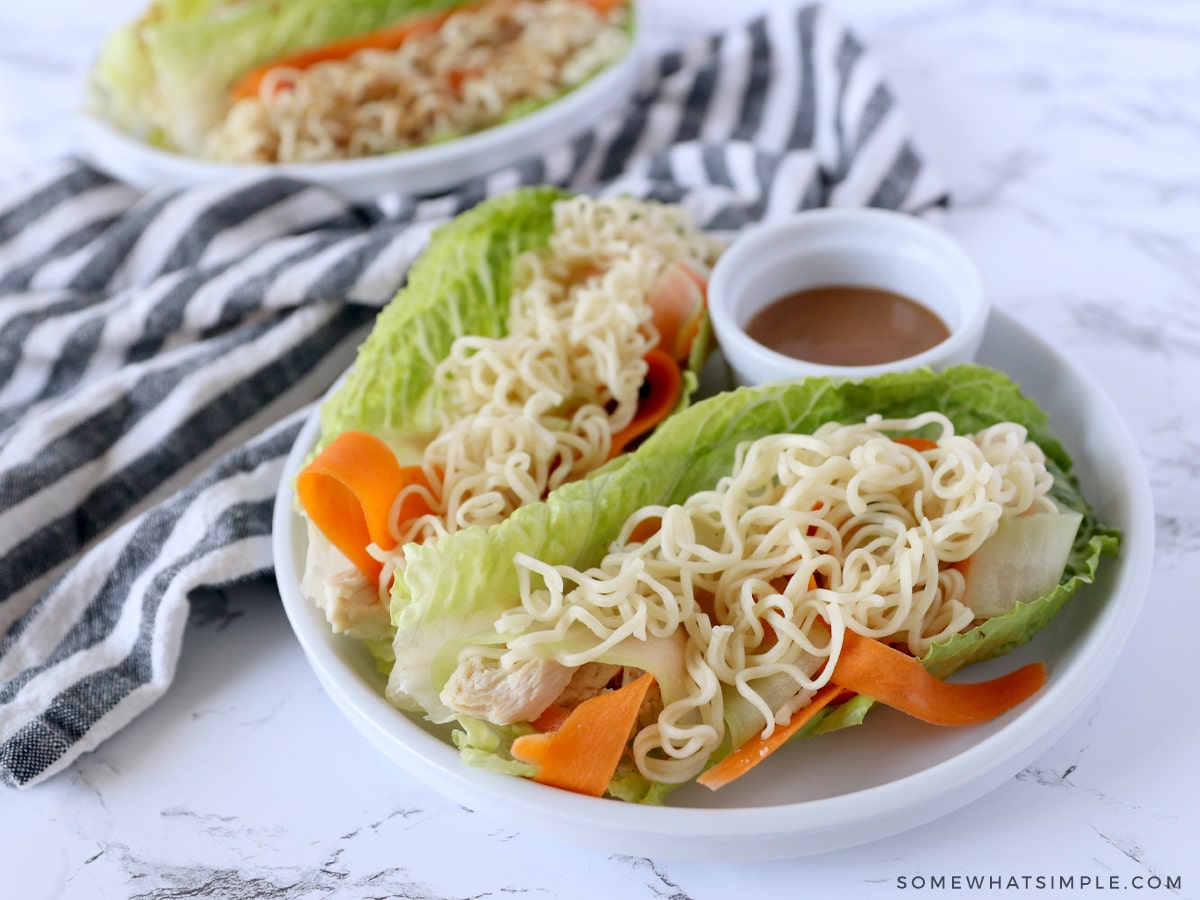 thai chicken lettuce wraps plated next to a striped towel