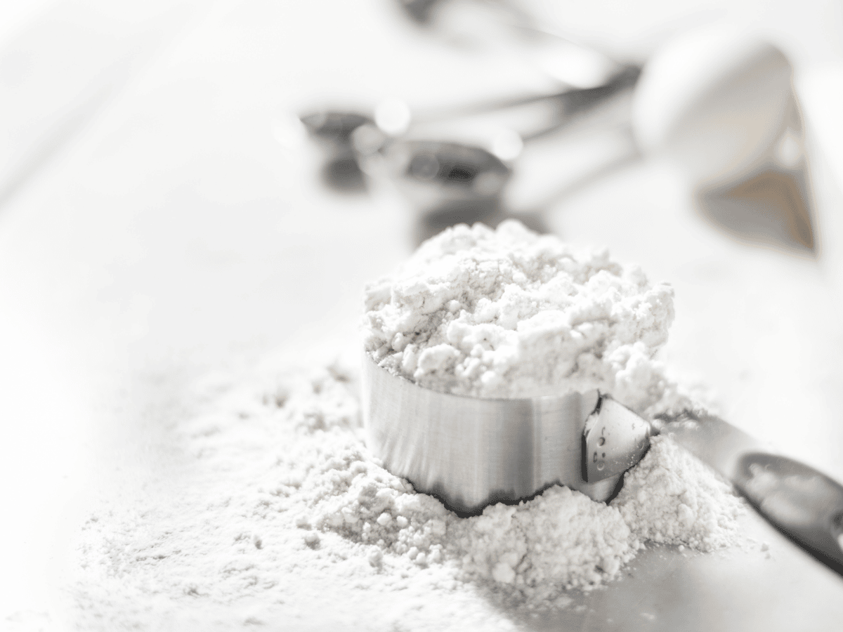 measuring cup full of flour on a white counter