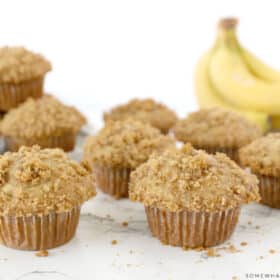 banana crumb muffins on a white counter with bananas in the background