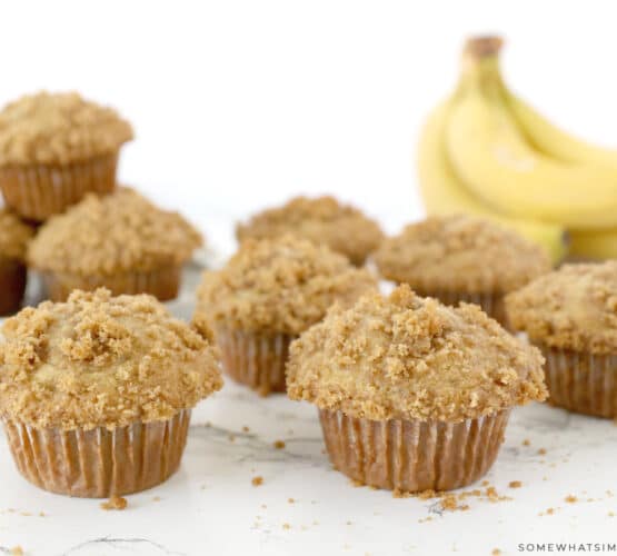 banana crumb muffins on a white counter with bananas in the background