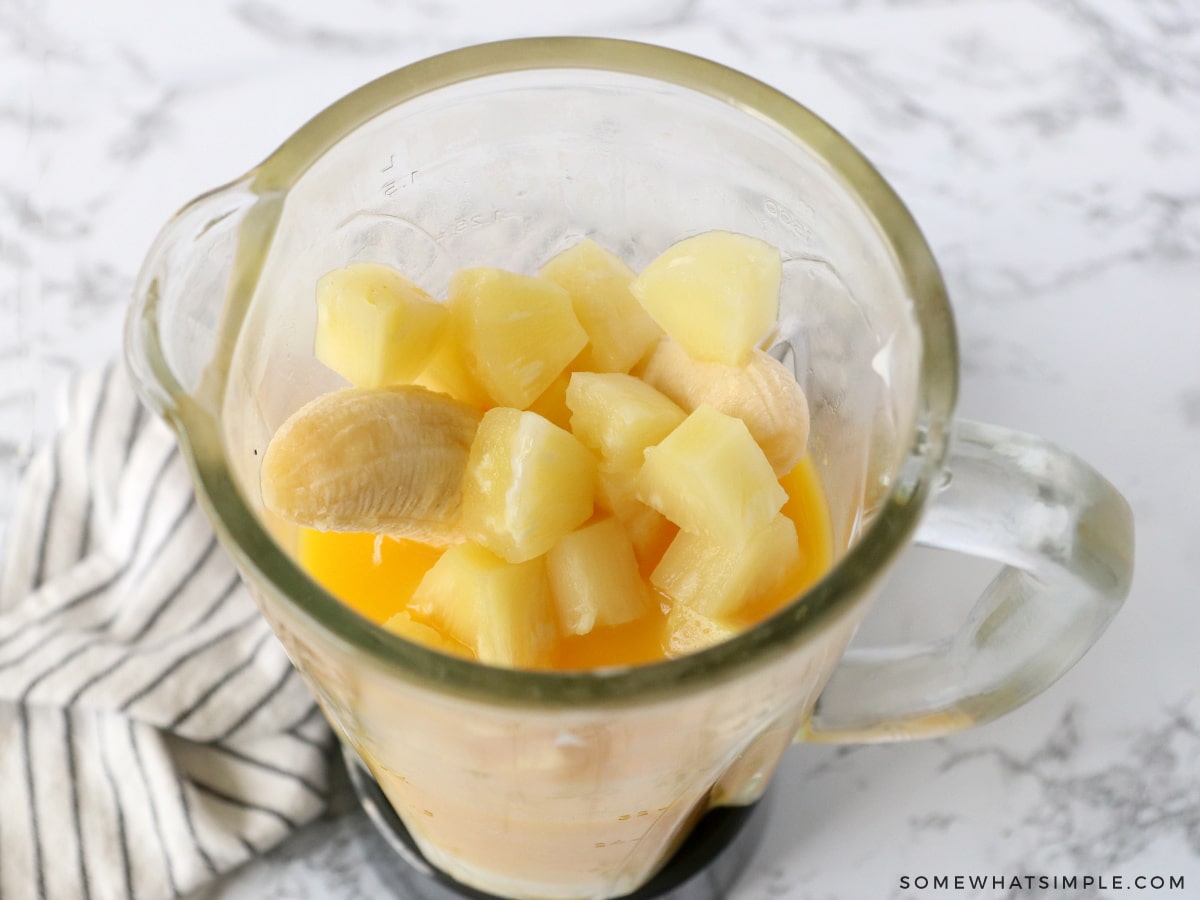 adding banana smoothie ingredients to a blender