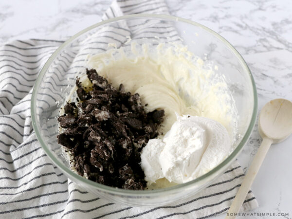 folding in crushed oreos into a bowl of frosting