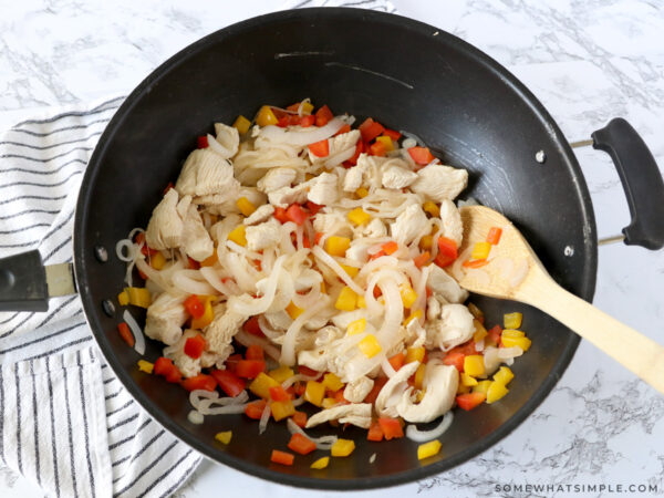 stirring chicken and veggies in a big pan