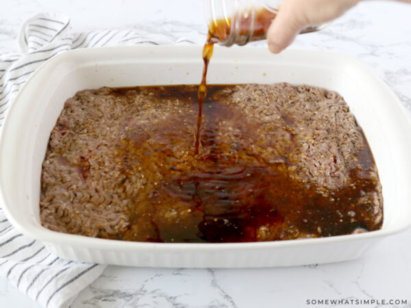 adding teriyaki sauce to the top of raw ground beef