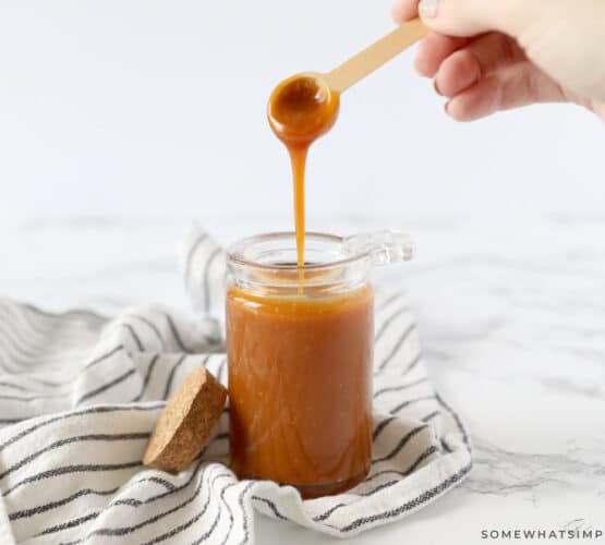 homemade salted caramel in a glass jar with wood spoon