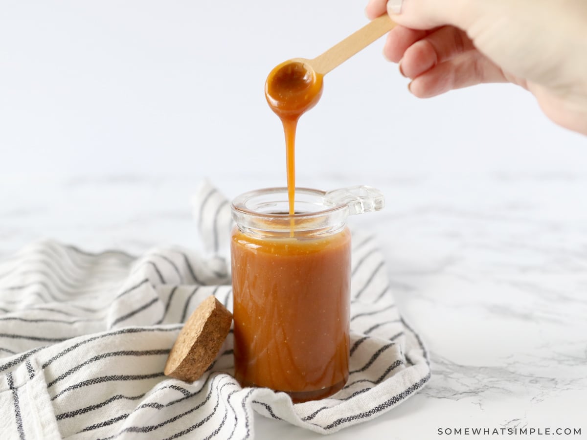 homemade salted caramel in a glass jar with wood spoon