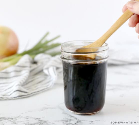 dipping a wooden spoon into a small jar of teriyaki sauce