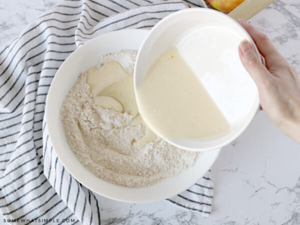 adding wet ingredients to the dry ingredients in a bowl of batter