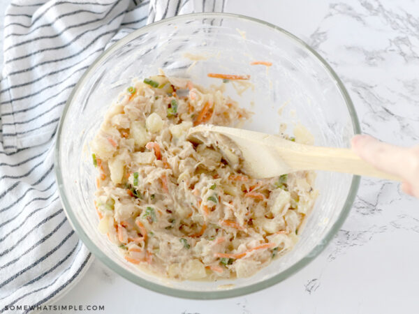 adding ingredients to a bowl and mixing it with a wooden spoon