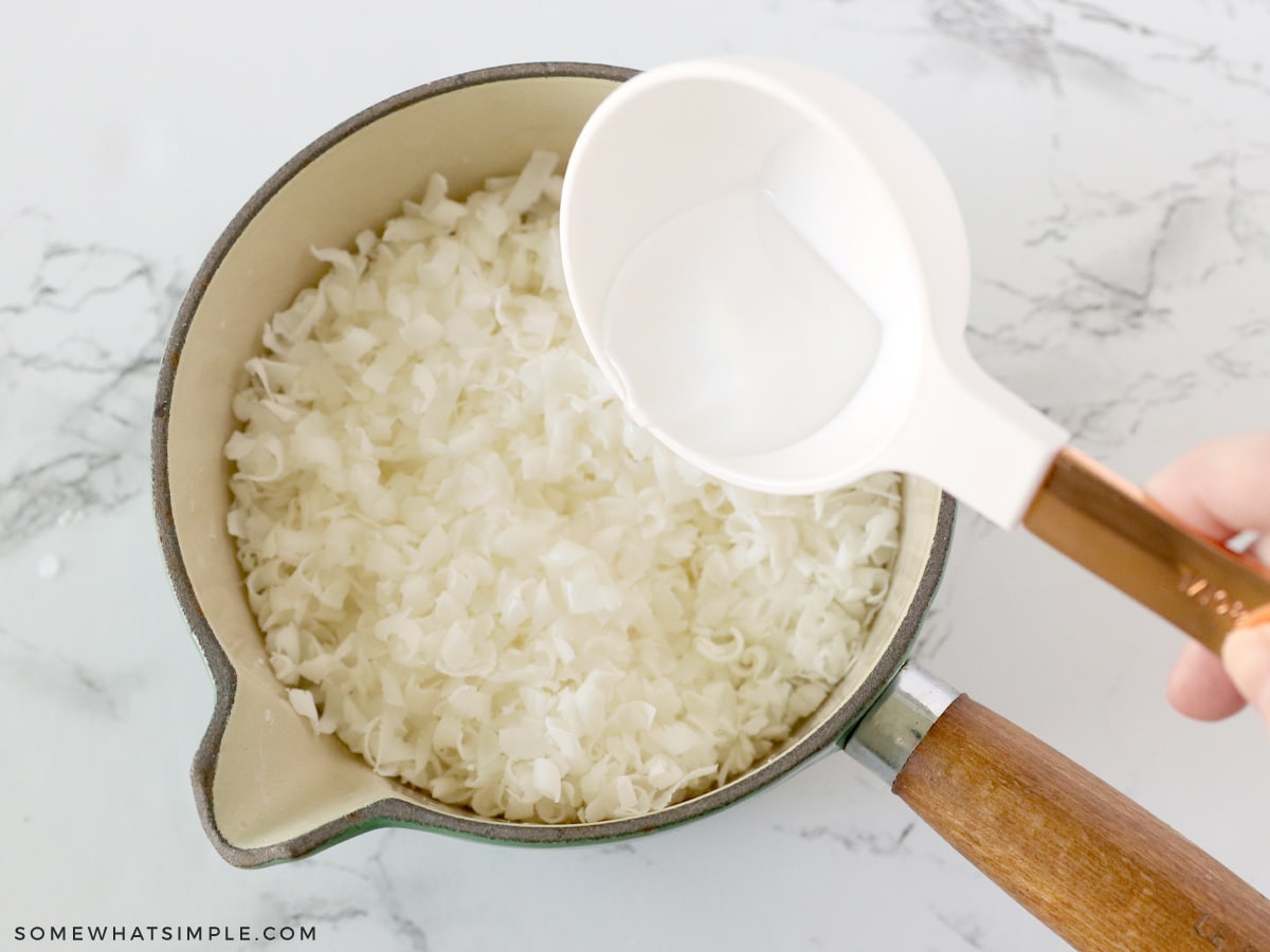 pouring coconut oil in a saucepan full of shaved soap