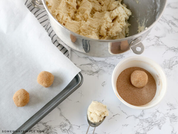 rolling cookie dough into a cinnamon sugar mixture