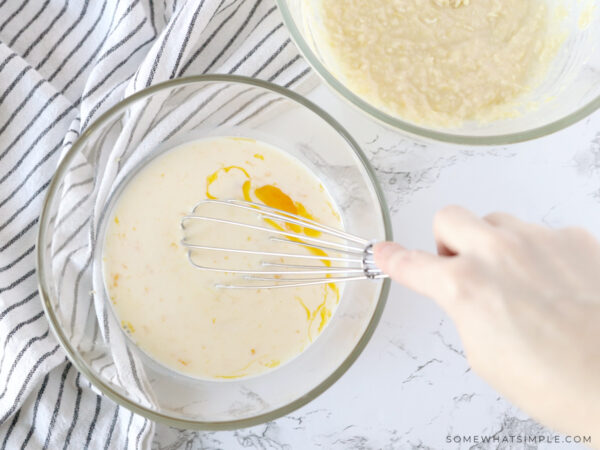 adding eggs to a glass mixing bowl