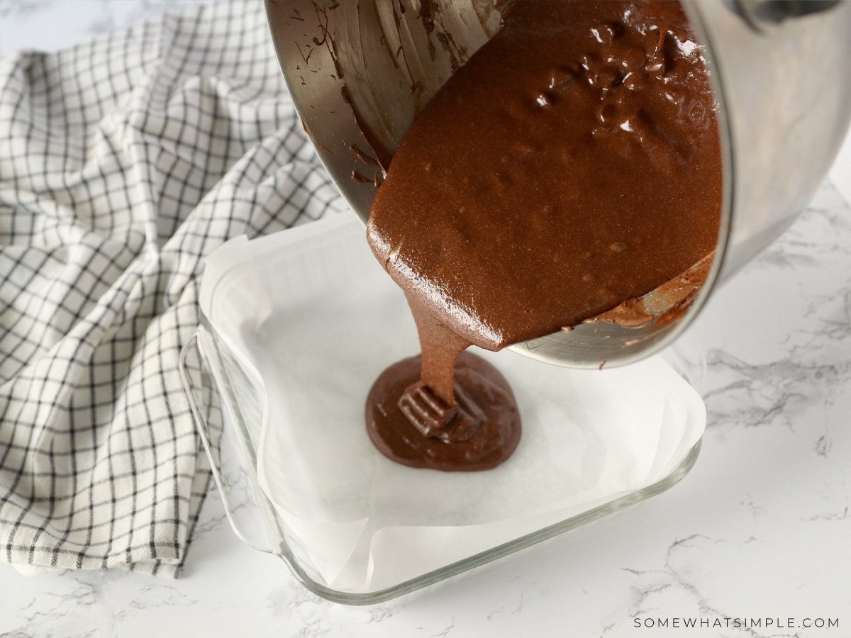 pouring brownie mix into a prepared pan