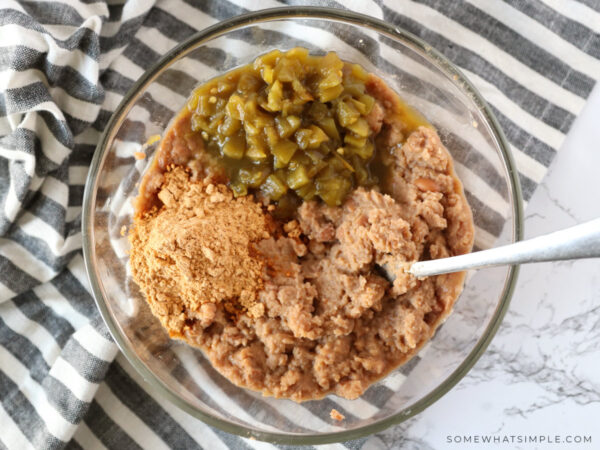 mixing refried beans with Mexican spices in a glass bowl