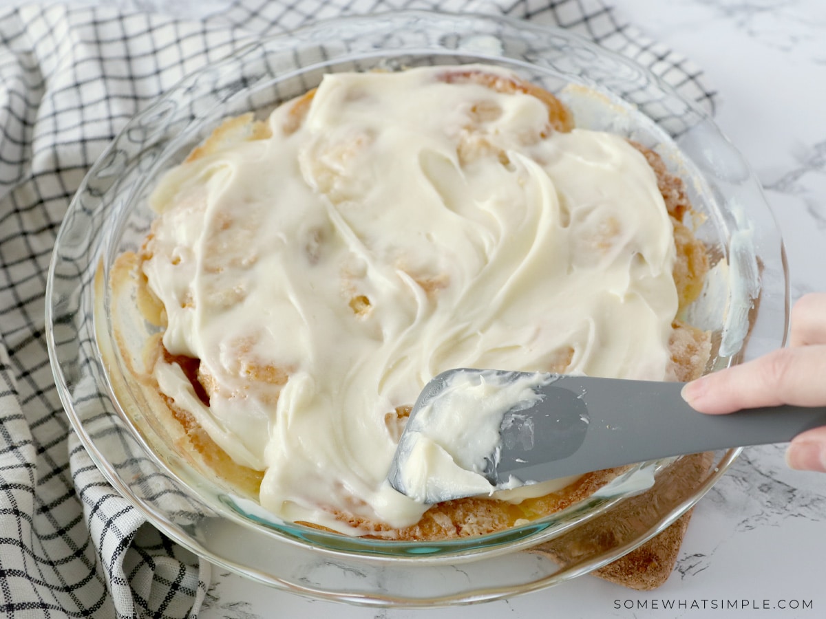 spreading frosting onto orange rolls