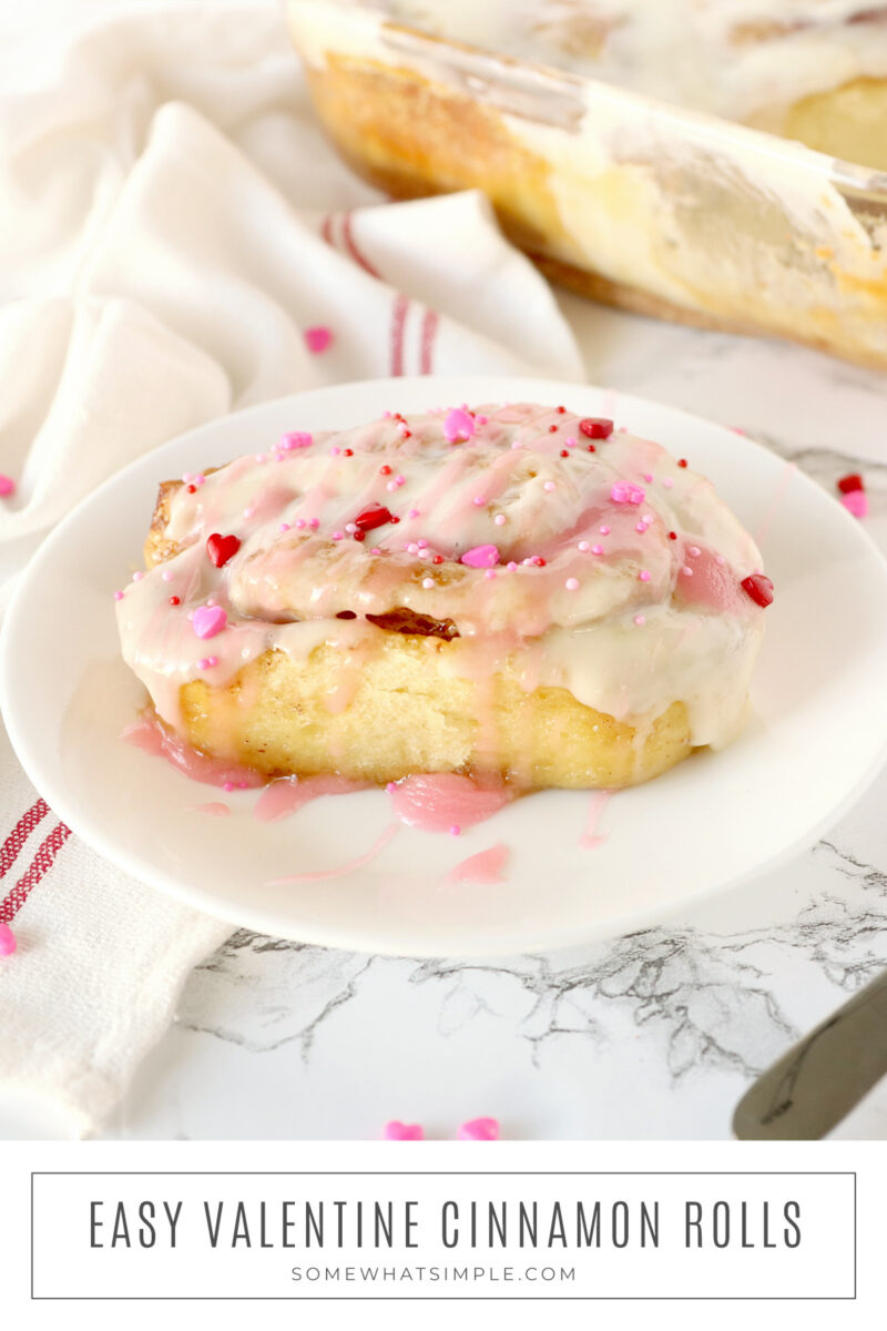 long image of a pink frosted cinnamon roll for valentines day