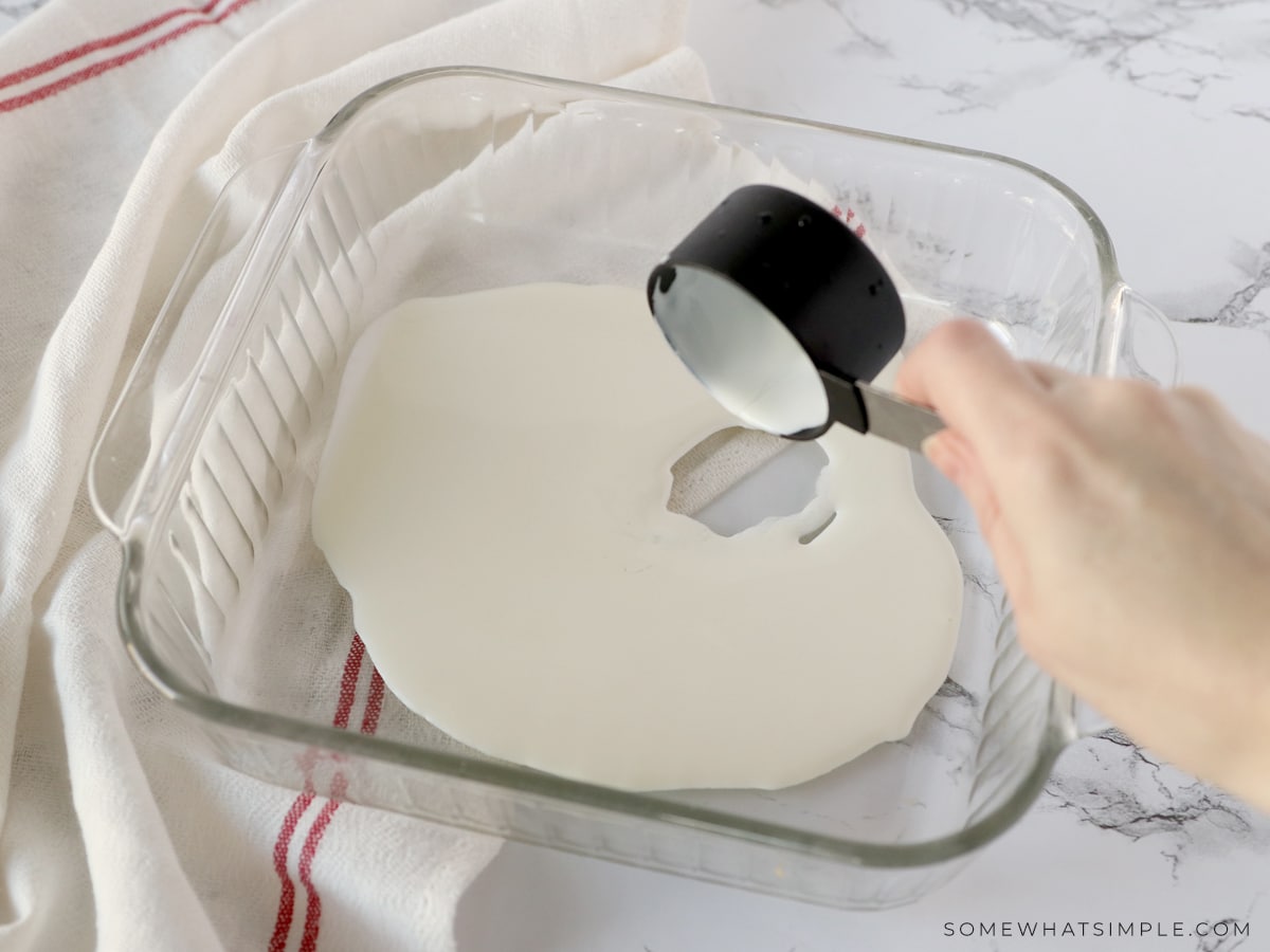 pouring whipping cream in the bottom of a casserole dish