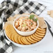 buffalo chicken salad in a white bowl surrounded by crackers