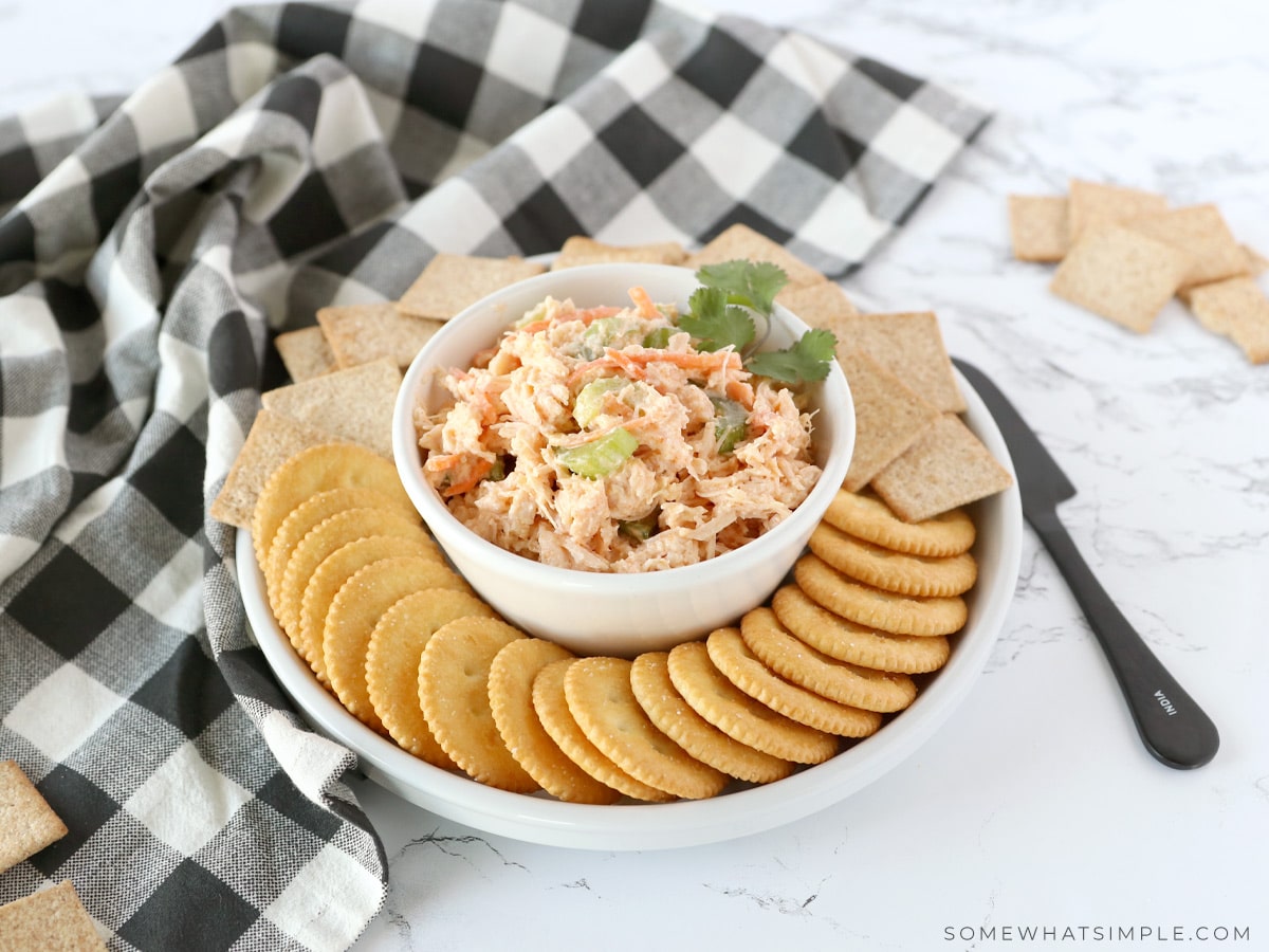 buffalo chicken salad in a white bowl surrounded by crackers