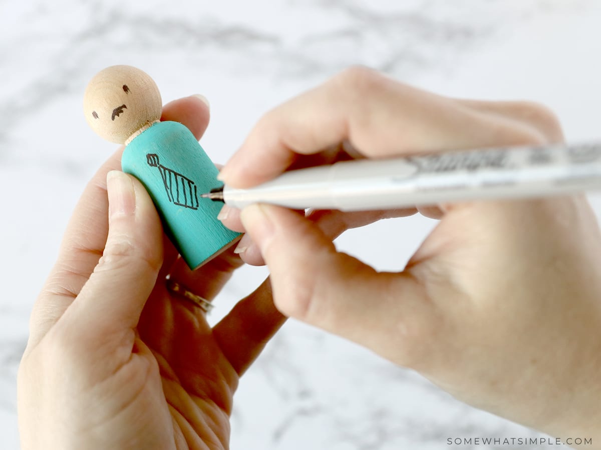 drawing clothing accessories onto wooden spool dolls
