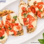 plated chicken breasts with cheese and bruschetta on top