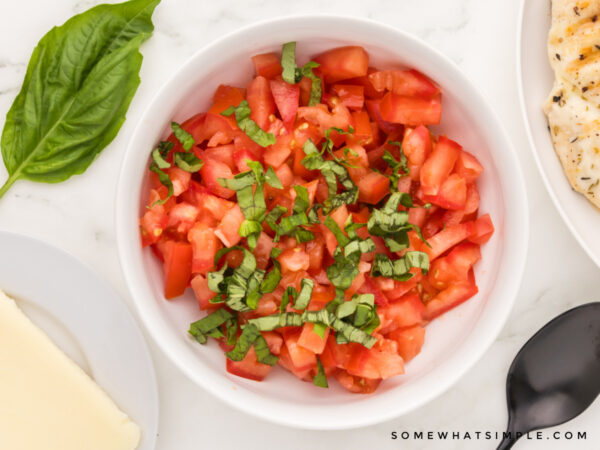 bowl of bruschetta next to grilled chicken