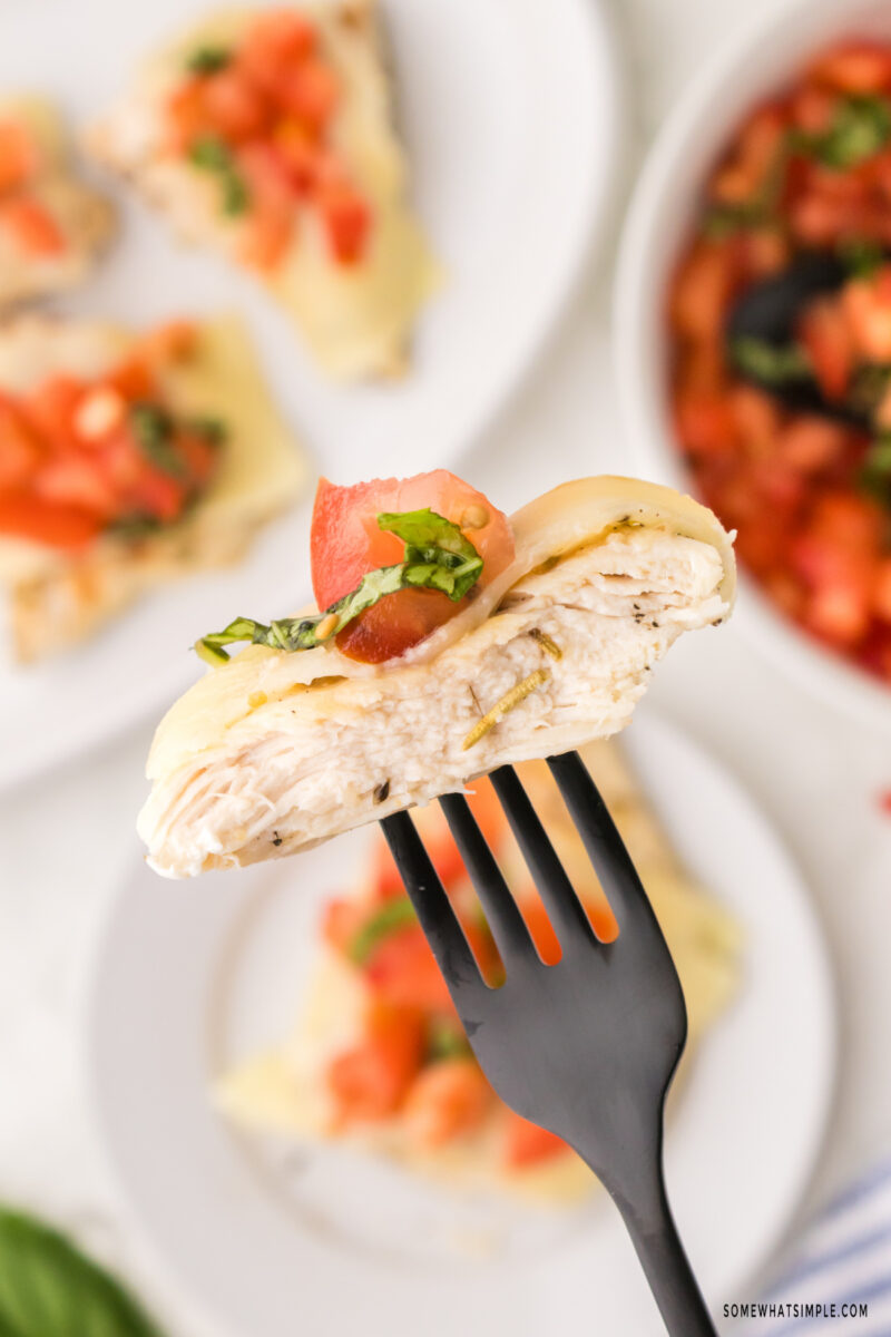 piece of chicken on a fork with the full dish in the background