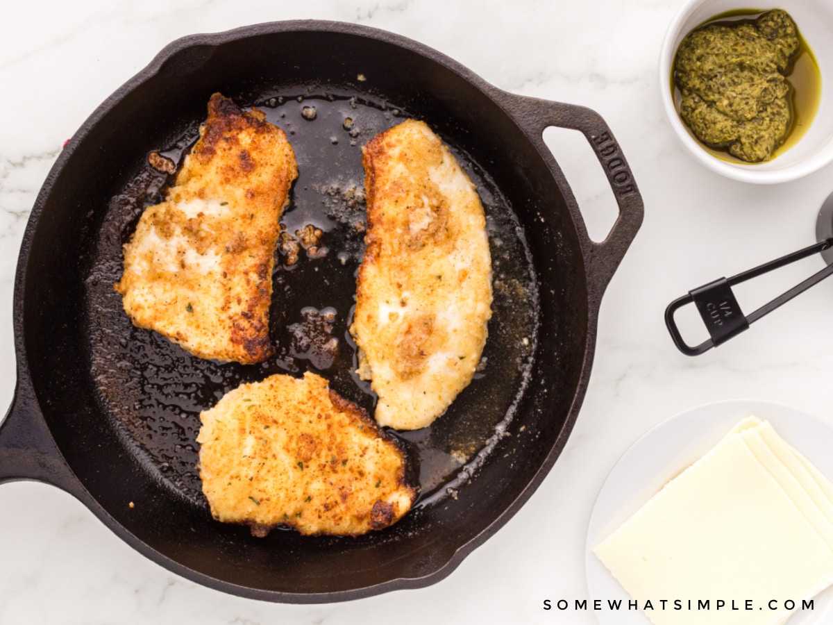 cooking chicken breasts in a skillet next to topping ingredients