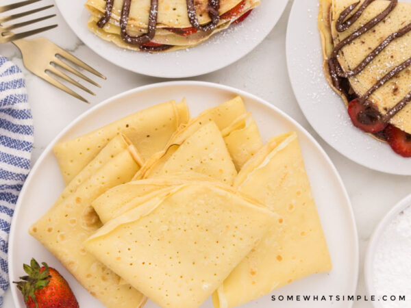 folded crepes on a white plate with other nutella crepes in the background